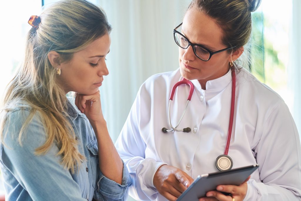 A doctor goes through a patient's health record on a tablet.