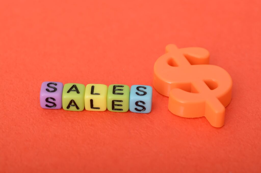 Alphabet beads with text SALES in orange background and dollar sign beside it.