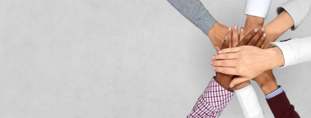 Employees from different races overlap hands in a circle.