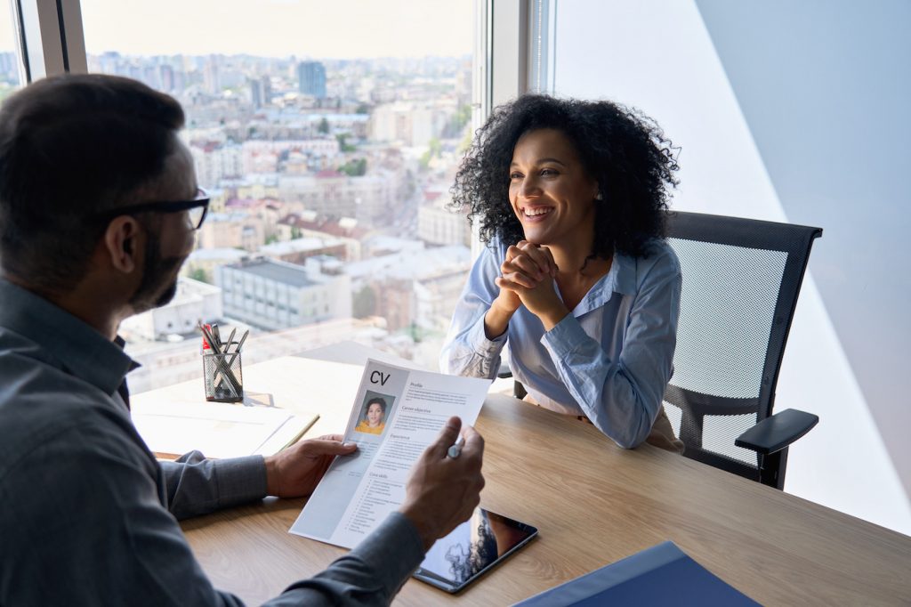 A recruiter interviews a job candidate in a corporate office setting.