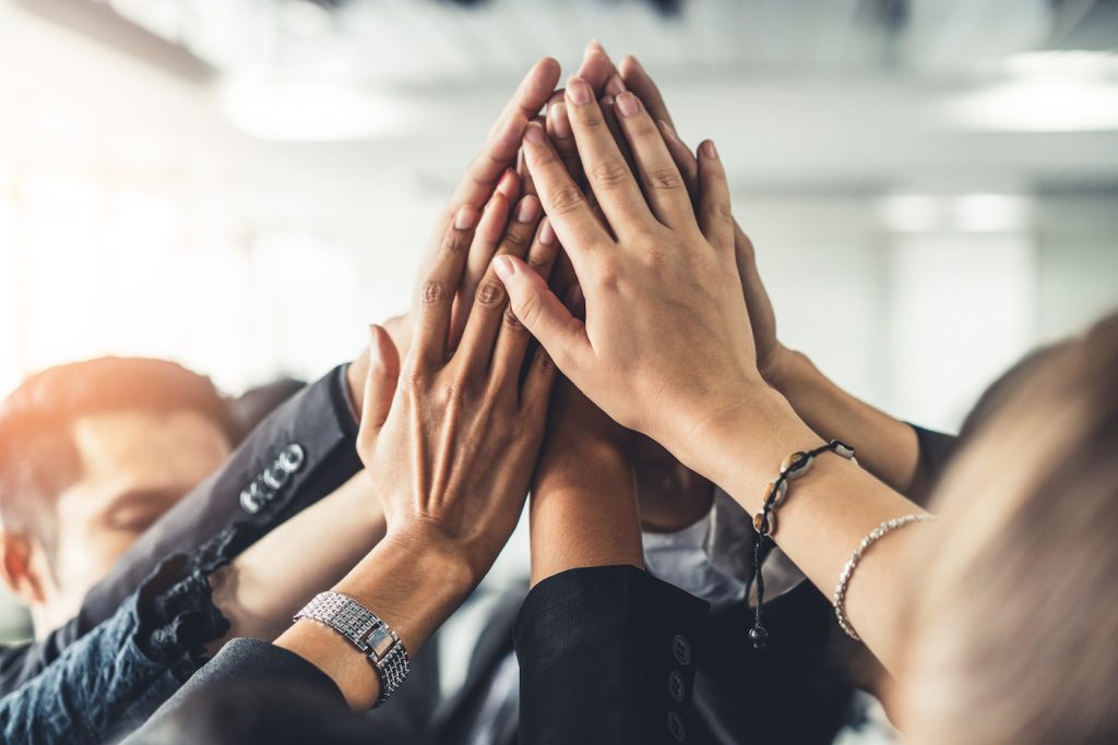 Business professionals overlap hands in a circle. Represents company culture vs. company values.