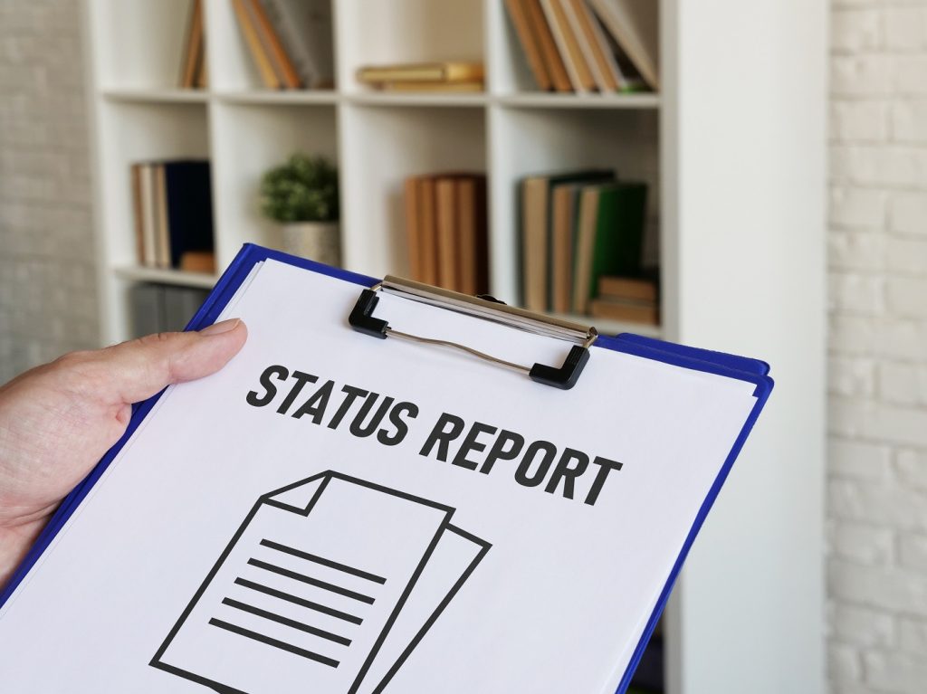 Person holding a clipboard with a status report sheet.