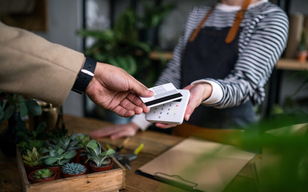 A customer handing over his credit card over the counter for payment.