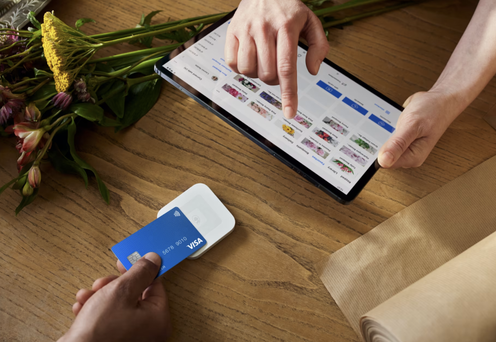 Customer tapping credit card on the Square contactless reader connected to a tablet with Square POS software.