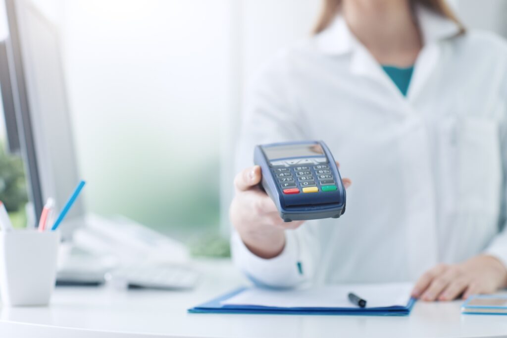 Pharmacist holding a payment terminal.