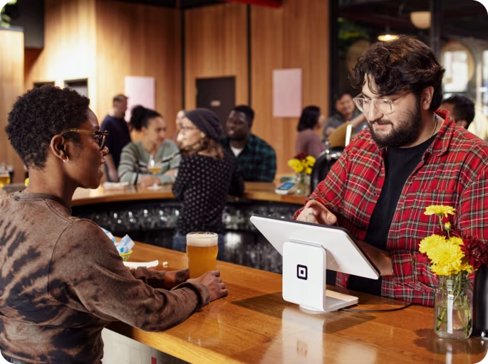 A bartender rings in a sale on a Square for Restaurants POS station.