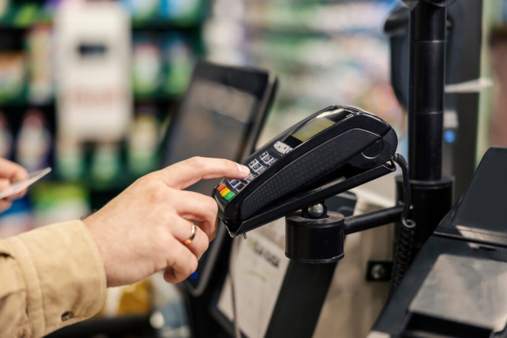 Close up of a man entering his credit card code on self-service cash out pos at supermarket.