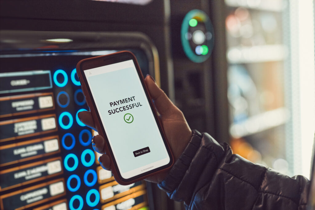 Customer paying for product at vending machine using contactless method of payment with mobile phone.