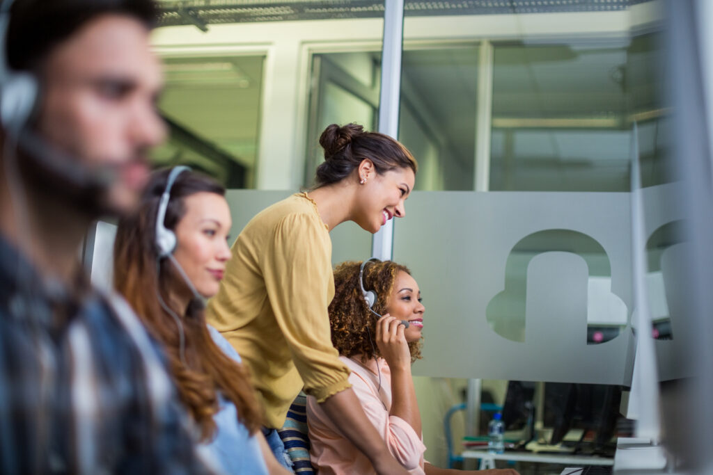 Female customer service executive interacting with her colleague at desk in office.