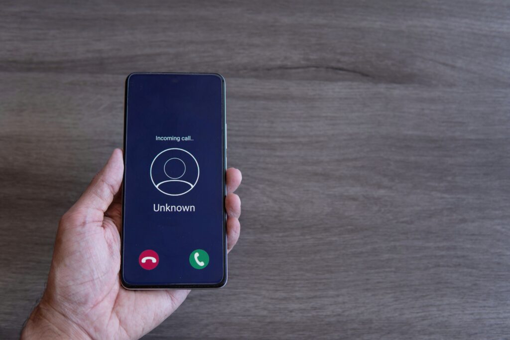 Top view image of hand holding smartphone and unknown incoming phone call on the screen.