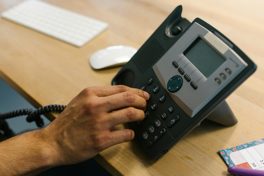 A hand dialing on a landline phone.