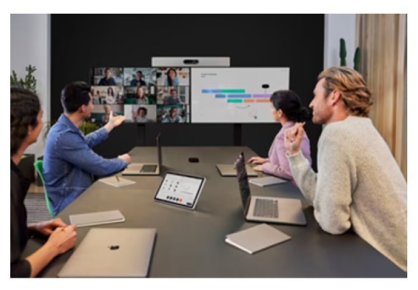 Conference room with in-person team members interacting with virtual attendees on an external display screen.