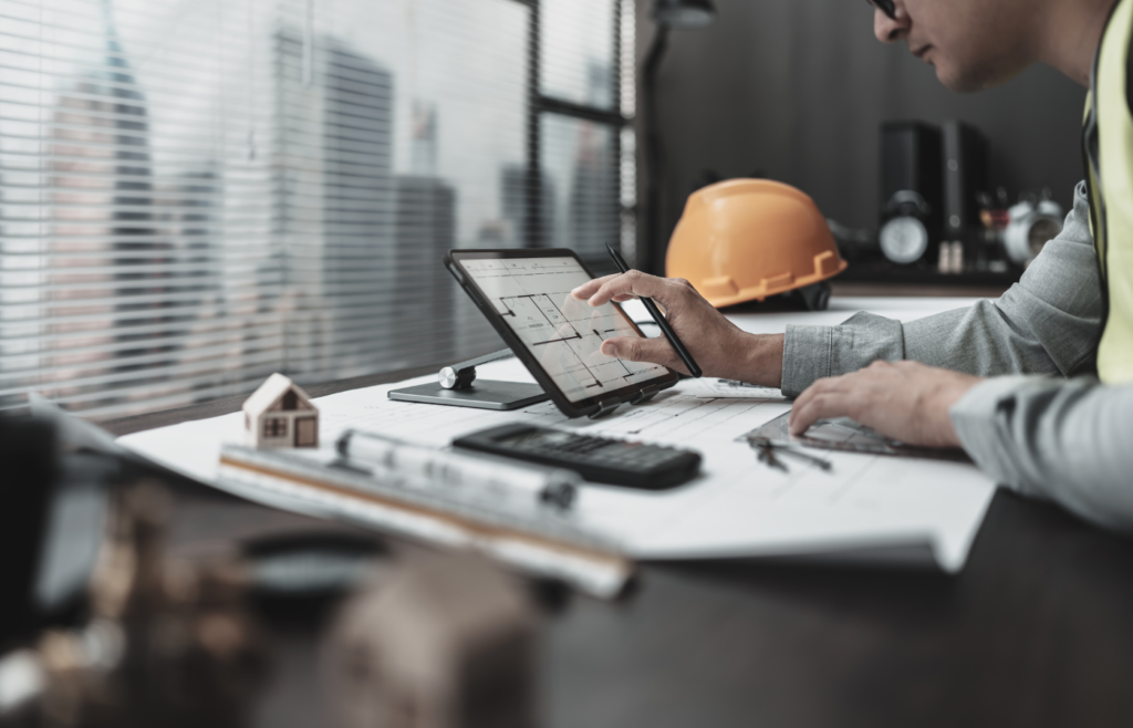 Modern construction planning: Engineer using a stylus and tablet for digital architectural design and 3D modeling in a professional workspace.