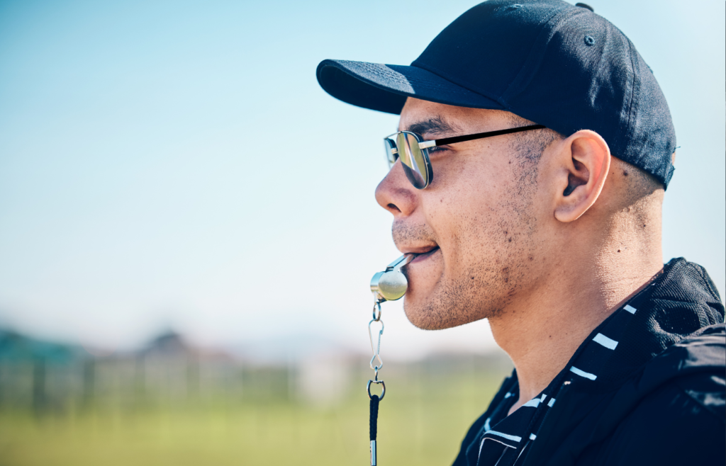 Coach, blowing whistle and sports training on a field with a man outdoor for competition or challen