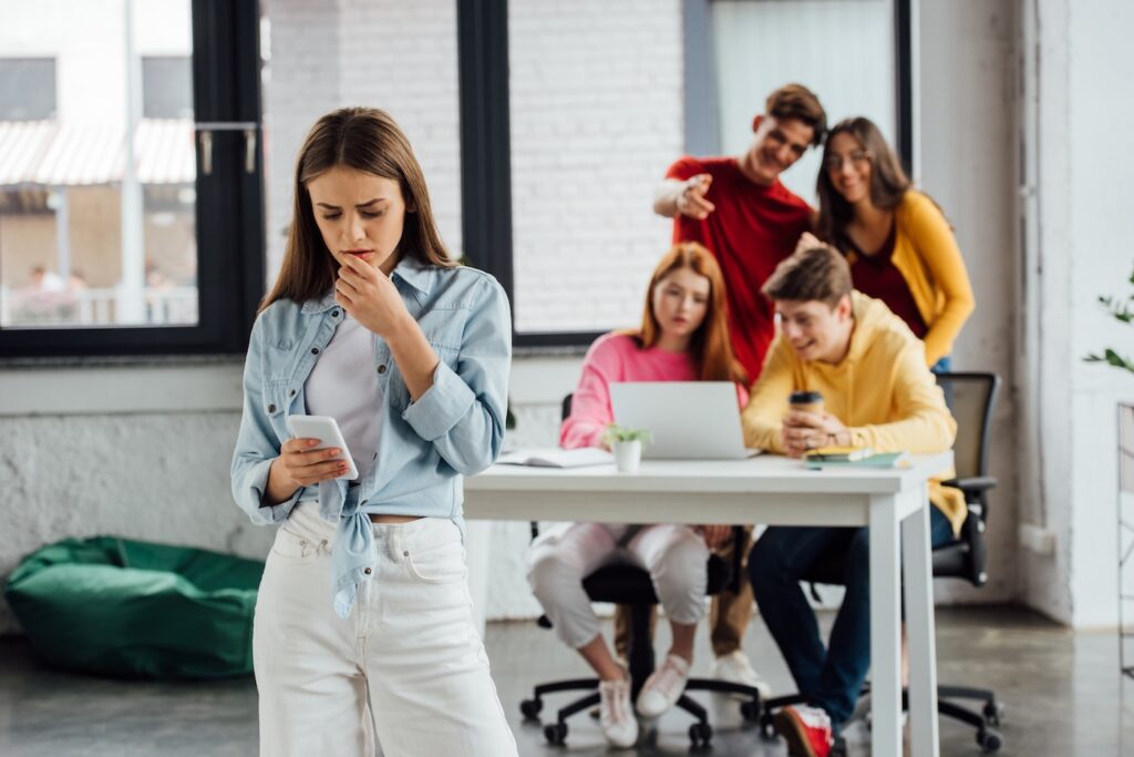 Distressed Gen Z employee looking at smartphone.
