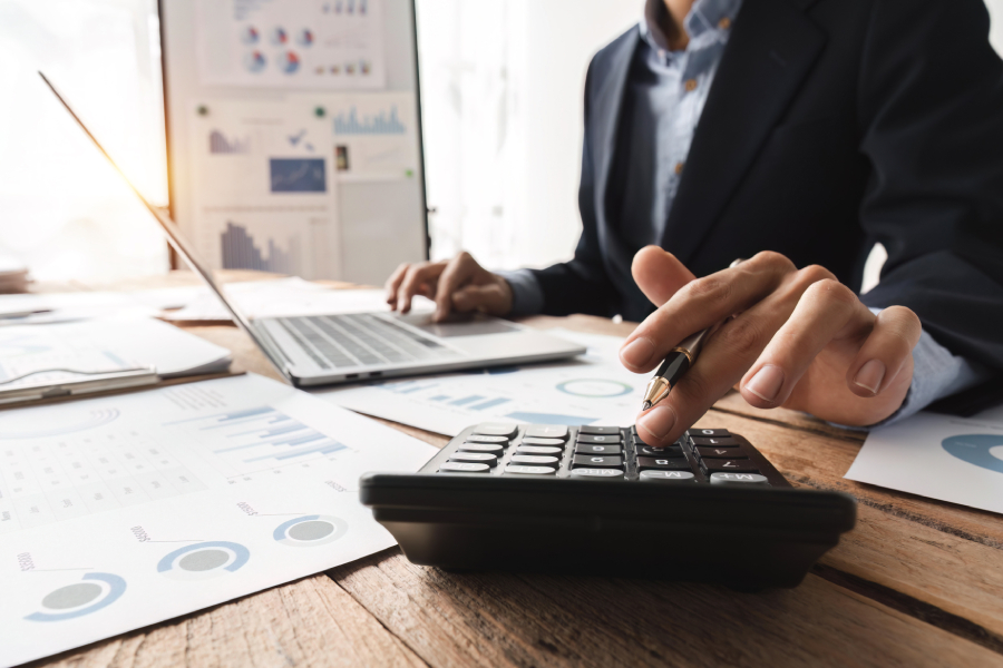 An accountant making computations on laptopand calculator.