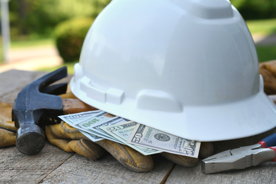 Hardhat with construction tools and cash money.