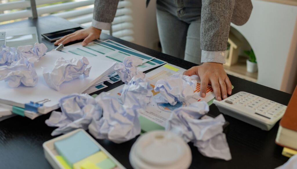 Overworked Professional at Desk Covered in Crumpled Papers