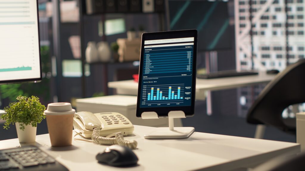 Best accounting automation software dashboard displaying income statements and financial bar charts on a tablet screen in a modern office setup.